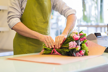 Image showing florist wrapping flowers in paper at flower shop