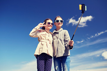 Image showing happy girls with smartphone selfie stick