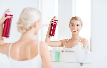 Image showing woman with hairspray styling her hair at bathroom