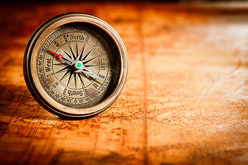 Image showing Vintage compass lies on an ancient world map.