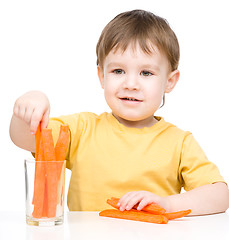 Image showing Little boy is eating carrot