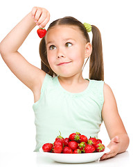 Image showing Cheerful little girl is eating strawberries