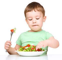 Image showing Cute little boy is eating vegetable salad