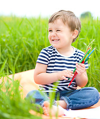 Image showing Little boy is playing with pencils