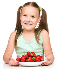 Image showing Cheerful little girl is eating strawberries