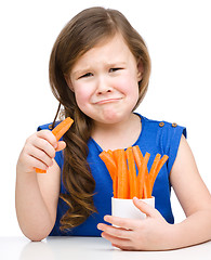 Image showing Cute little girl is eating carrot