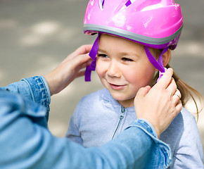 Image showing Mother is helping her daughter with safety helmet