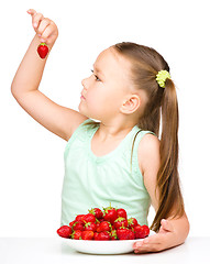 Image showing Cheerful little girl is eating strawberries