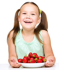 Image showing Cheerful little girl is eating strawberries