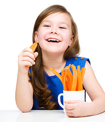 Image showing Cute little girl is eating carrot