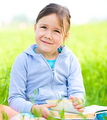 Image showing Little girl is reading a book outdoors