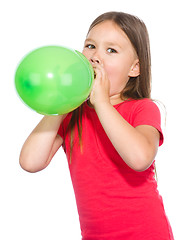 Image showing Little girl is inflating green balloon