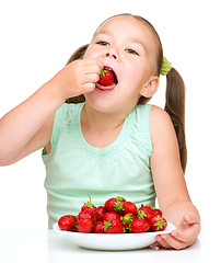 Image showing Little girl is eating strawberries