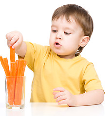 Image showing Little boy is eating carrot
