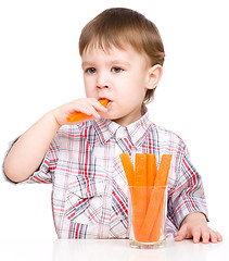 Image showing Little boy is eating carrot