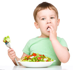 Image showing Cute little boy is eating vegetable salad