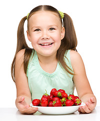 Image showing Cheerful little girl is eating strawberries