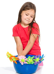 Image showing Little girl is playing with flowers
