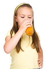 Image showing Little girl is drinking orange juice