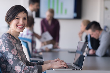 Image showing young business woman at office working on laptop with team on me