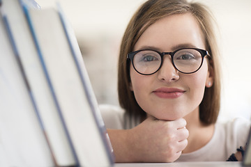 Image showing portrait of famale student selecting book to read in library