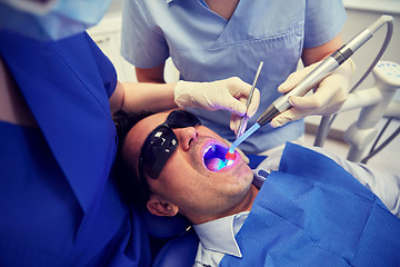 Image showing dentists treating male patient teeth at clinic