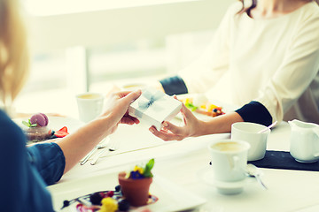 Image showing close up of women giving present at restaurant