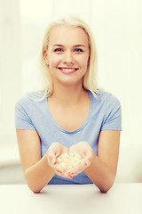 Image showing happy woman holding pills or capsules at home