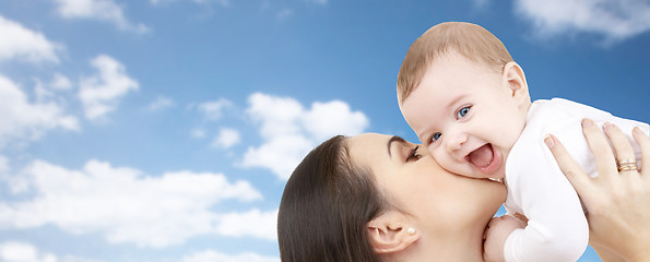 Image showing happy mother kissing her baby over blue sky