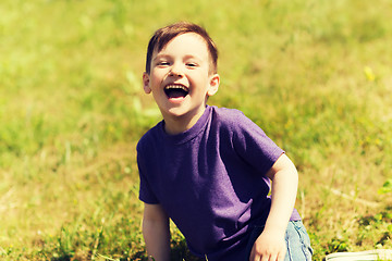 Image showing happy little boy sitting on grass outdoors