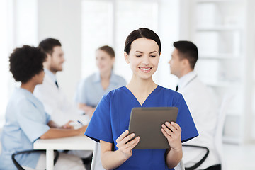 Image showing happy doctor with tablet pc over team at clinic