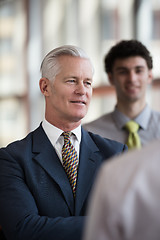 Image showing portrait of senior businessman as leader  with staff in backgrou