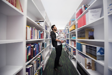 Image showing Student holding lot of books in school library