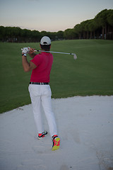 Image showing golfer hitting a sand bunker shot on sunset