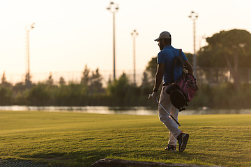 Image showing golfer  walking and carrying golf  bag at beautiful sunset