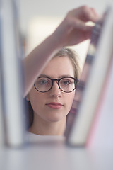 Image showing portrait of famale student selecting book to read in library