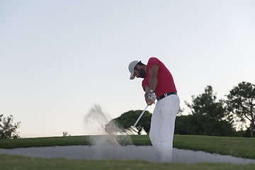 Image showing golfer hitting a sand bunker shot on sunset