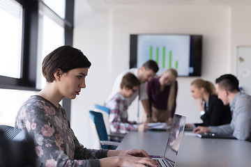 Image showing young business woman at office working on laptop with team on me