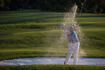 Image showing golfer hitting a sand bunker shot on sunset