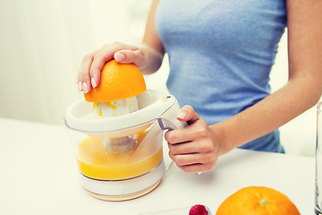 Image showing close up of woman squeezing orange juice at home