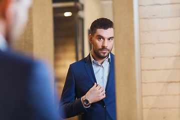 Image showing man trying jacket on at mirror in clothing store