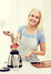 Image showing smiling woman with blender preparing shake at home