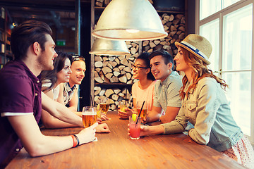 Image showing happy friends with drinks talking at bar or pub