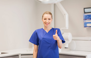 Image showing happy female dentist showing thumbs up at clinic
