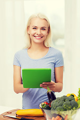 Image showing smiling young woman with tablet pc cooking at home