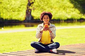 Image showing happy african young woman messaging on smartphone