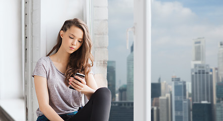 Image showing sad pretty teenage girl with smartphone texting