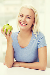 Image showing happy woman eating green apple at home