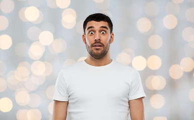 Image showing scared man in white t-shirt over lights background