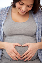 Image showing happy pregnant woman making heart gesture at home